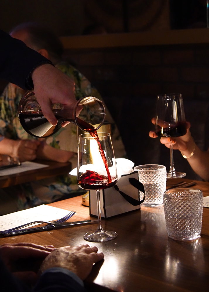 Pouring wine from a carafe into a glass.