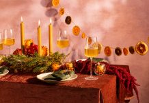 A table scape with earthy decor, candles, and wine glasses.