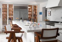 Wide-plank white-oak flooring complements the Orley Shabahang runners. The teak stools have arms and include white boucle seats and backs.