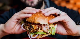 Young man eating a cheeseburger.