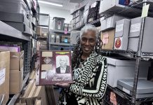 DSC director and director of collections Michelle Jahra McKinney holds up a scrapbook from the DSC archives, currently housed in Detroit’s WGPR 107.5 FM building.