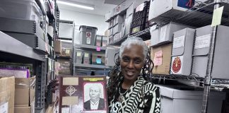 DSC director and director of collections Michelle Jahra McKinney holds up a scrapbook from the DSC archives, currently housed in Detroit’s WGPR 107.5 FM building.