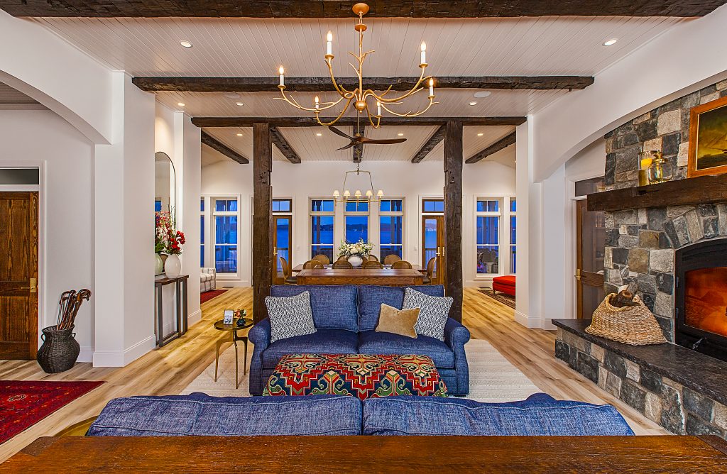 A cozy living room with blue sofas, a stone fireplace, and a chandelier.