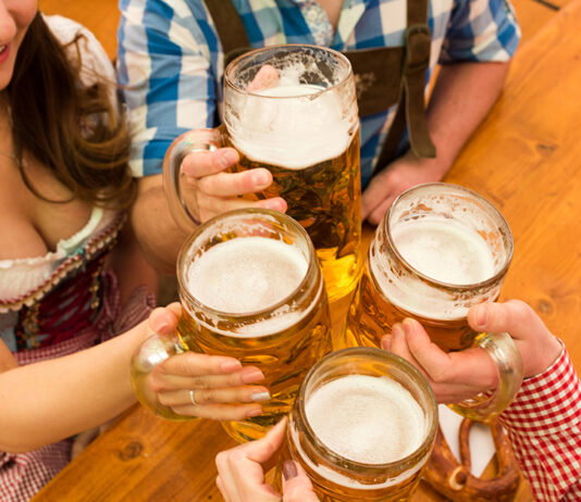 Prost! Celebrating Oktoberfest in Metro Detroit Young couple toasting in Oktoberfest beer tent.