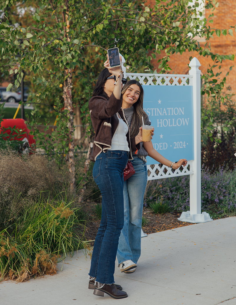 Attendees dressed like Lorelai and Rory Gilmore taking a selfie in front of a Destination Starz Hollow sign.