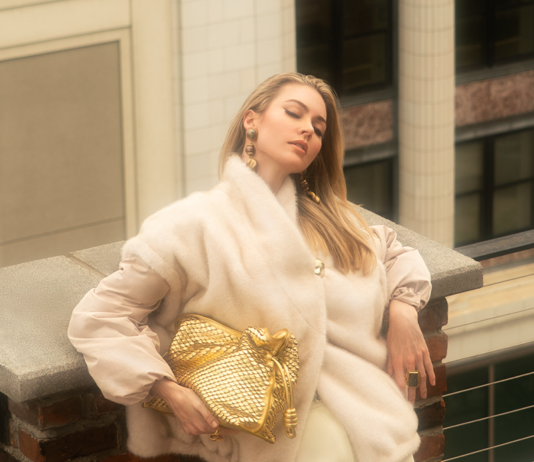 Fall Fashion 2026: Elevated Elegance Model posing in a furry puffer jacket, while holding a gold handbag.