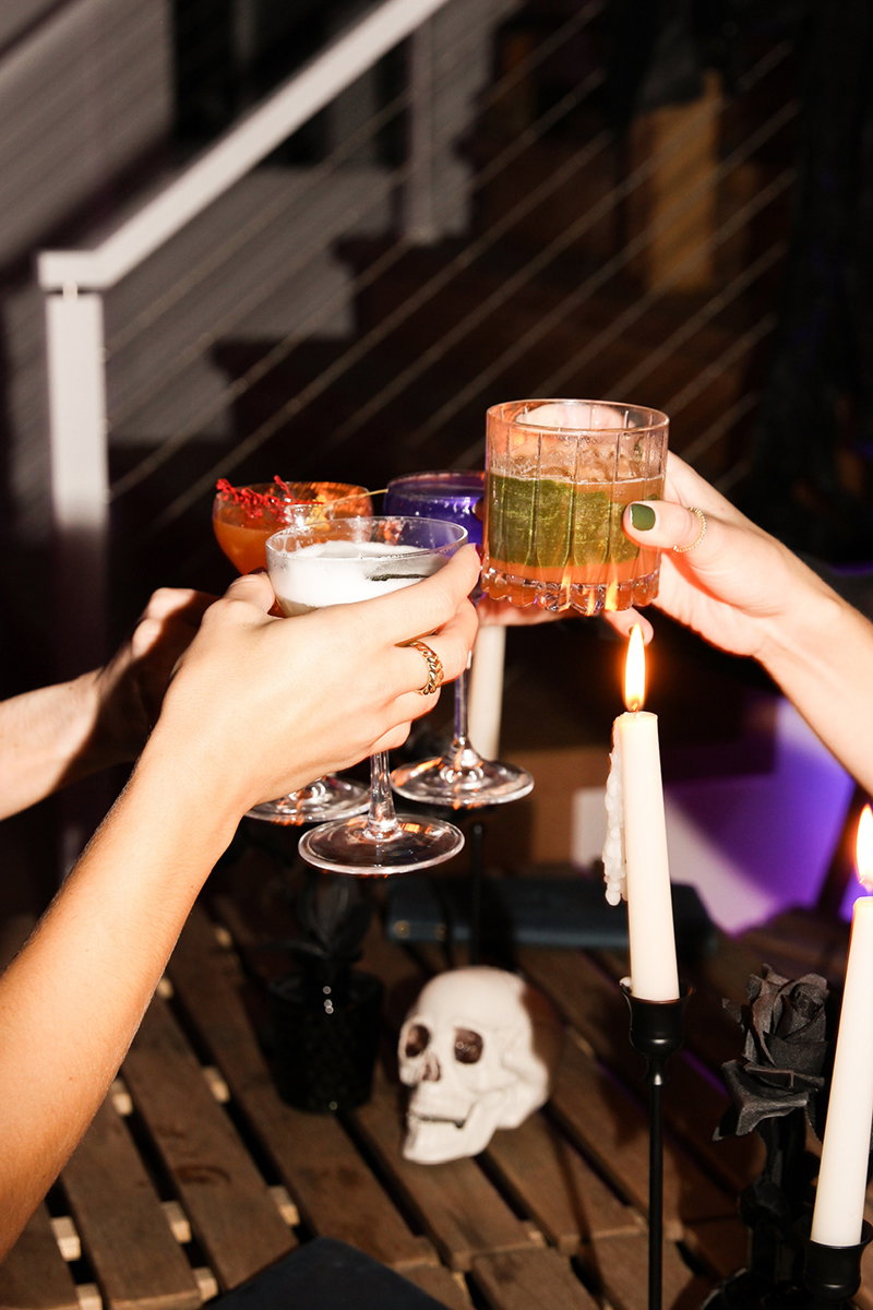 People clinking Halloween-themed cocktails.