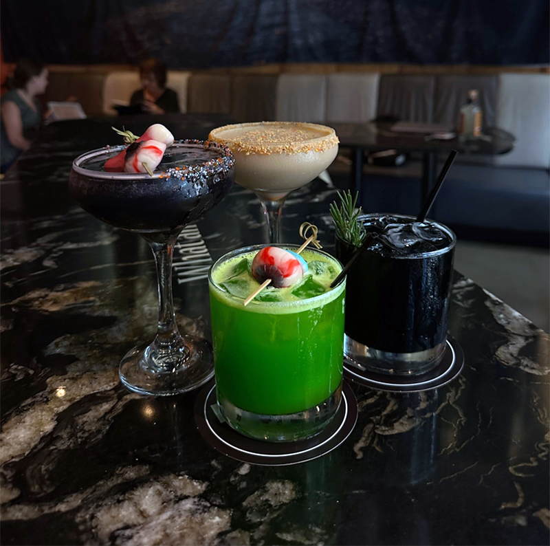 Four different Halloween-themed cocktails on a dark surface.
